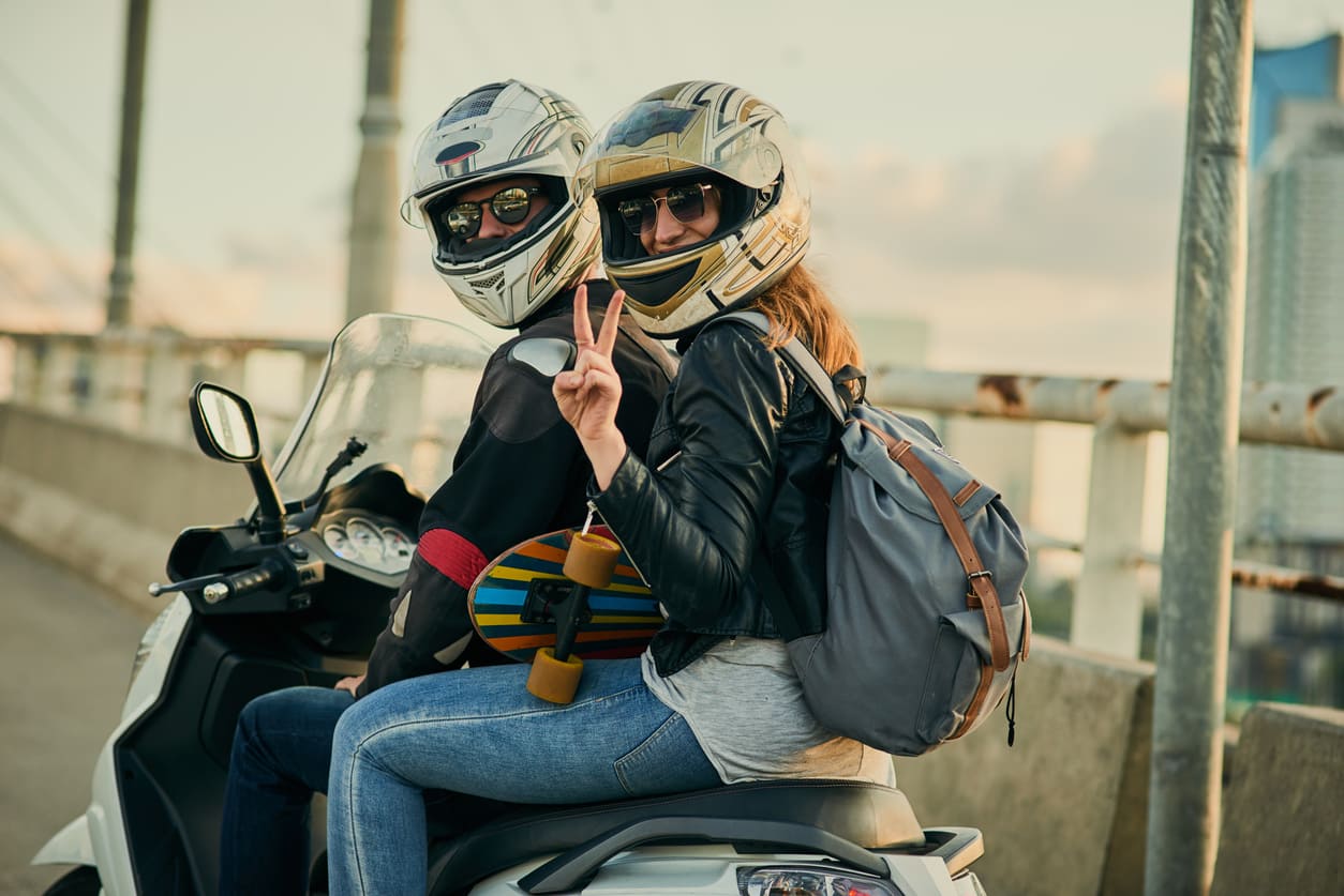 Una pareja de moteros equipados saliendo de ruta en una motocicleta con la placa L de conductor novel, demostrando que sí se puede llevar pasajero.