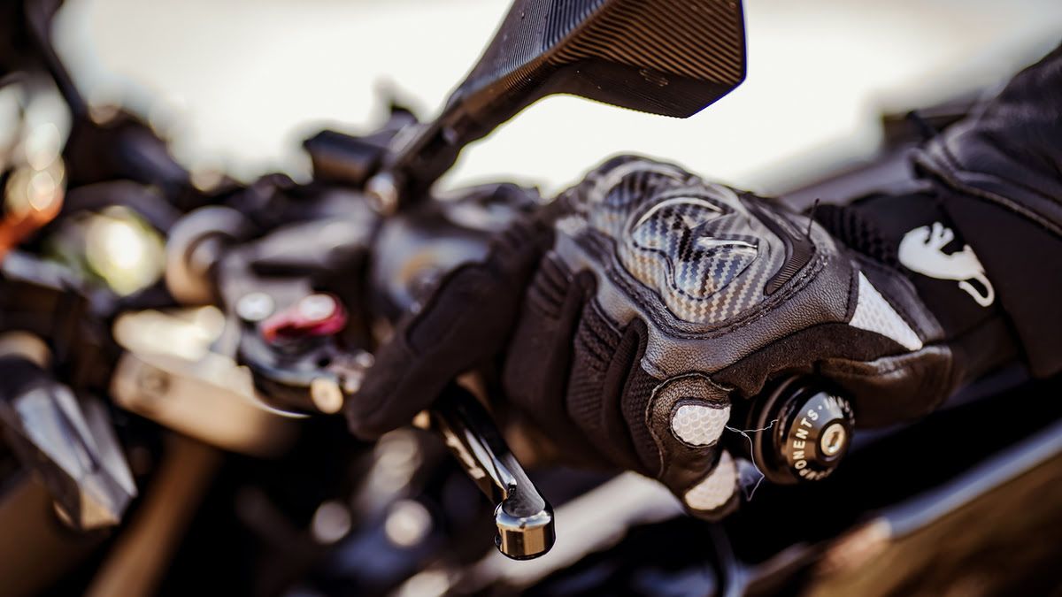 Detalle de la mano izquierda de un alumno de la autoescuela MotoCircuito accionando la maneta del embrague de una motocicleta de marchas en el circuito de Móstoles.