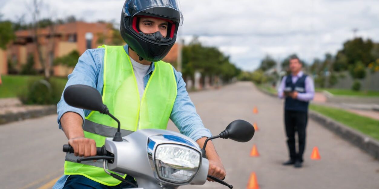 Examinador de la DGT anotando en su tablet mientras un alumno de la autoescuela MotoCircuito realiza correctamente el zigzag de jalones en Móstoles.
