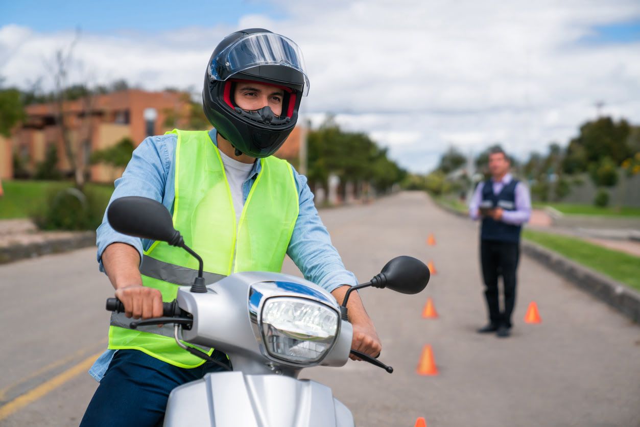 Examinador de la DGT anotando en su tablet mientras un alumno de la autoescuela MotoCircuito realiza correctamente el zigzag de jalones en Móstoles.