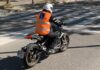 Motorista de la autoescuela MotoCircuito realizando prácticas de circulación en ciudad, seguido de cerca por el coche del profesor en Móstoles.