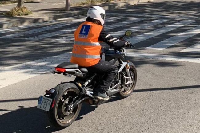 examen-circulacion-calle-moto-dgt-mostoles-madrid Motorista de la autoescuela MotoCircuito realizando prácticas de circulación en ciudad, seguido de cerca por el coche del profesor en Móstoles.