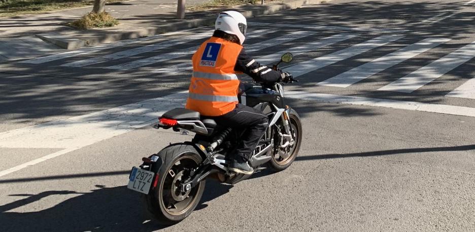Motorista de la autoescuela MotoCircuito realizando prácticas de circulación en ciudad, seguido de cerca por el coche del profesor en Móstoles.