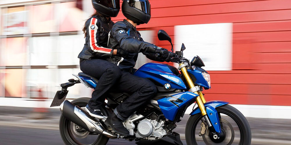 Detalle de dos personas montadas en una motocicleta, mostrando la postura correcta del pasajero con los pies en las estriberas, aprendida en la autoescuela MotoCircuito.