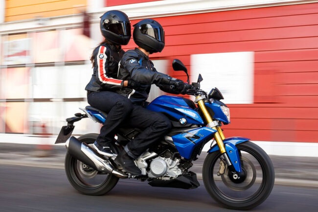 Detalle de dos personas montadas en una motocicleta, mostrando la postura correcta del pasajero con los pies en las estriberas, aprendida en la autoescuela MotoCircuito.