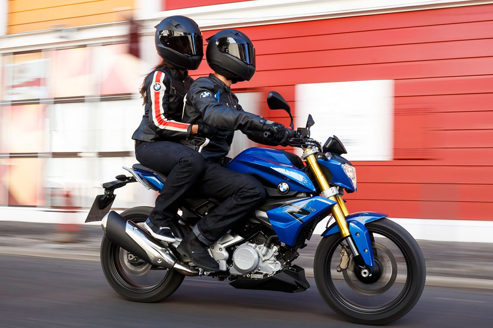 Detalle de dos personas montadas en una motocicleta, mostrando la postura correcta del pasajero con los pies en las estriberas, aprendida en la autoescuela MotoCircuito.