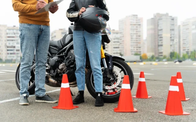 Un alumno feliz chocando la mano con su profesor de la autoescuela MotoCircuito en Móstoles tras aprobar su carnet de moto A2 a la primera, ahorrando dinero en tasas.