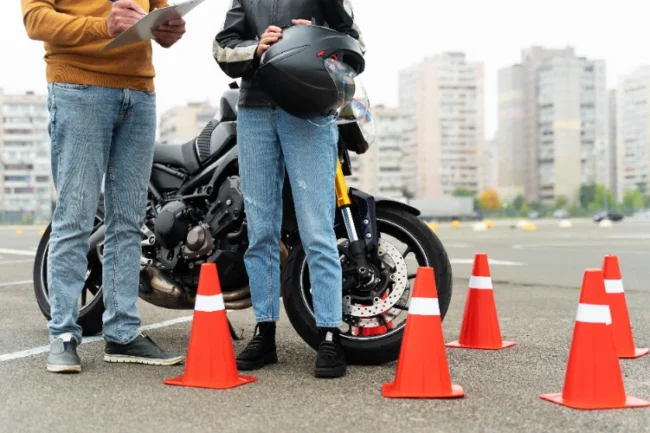 Un alumno feliz chocando la mano con su profesor de la autoescuela MotoCircuito en Móstoles tras aprobar su carnet de moto A2 a la primera, ahorrando dinero en tasas.