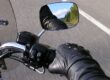 Detalle de la bota de un motorista accionando la palanca de cambios hacia arriba y la mano apretando el embrague, practicando la técnica en el circuito de la autoescuela MotoCircuito.