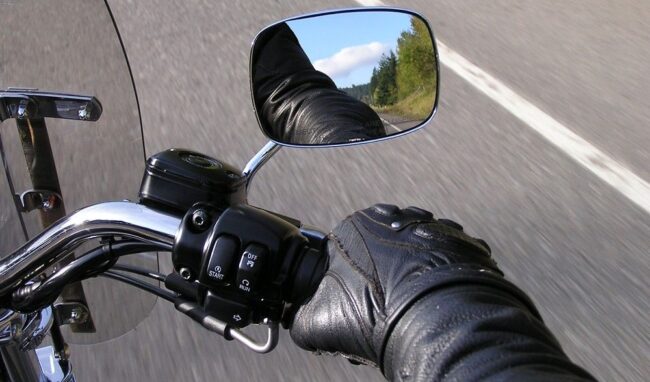 Detalle de la bota de un motorista accionando la palanca de cambios hacia arriba y la mano apretando el embrague, practicando la técnica en el circuito de la autoescuela MotoCircuito.