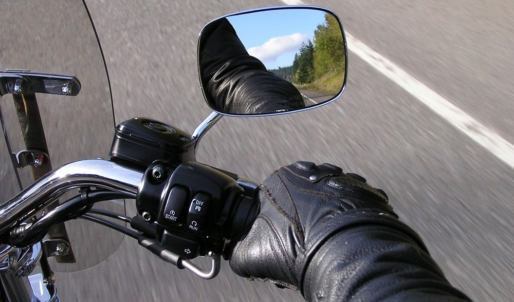 Detalle de la bota de un motorista accionando la palanca de cambios hacia arriba y la mano apretando el embrague, practicando la técnica en el circuito de la autoescuela MotoCircuito.
