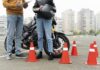 Alumno de la autoescuela MotoCircuito sonriendo y mostrando la placa de la 'L' junto a su profesor en Móstoles, celebrando la obtención de su carnet de moto A2 en tiempo récord.