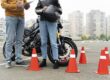Alumno de la autoescuela MotoCircuito sonriendo y mostrando la placa de la 'L' junto a su profesor en Móstoles, celebrando la obtención de su carnet de moto A2 en tiempo récord.