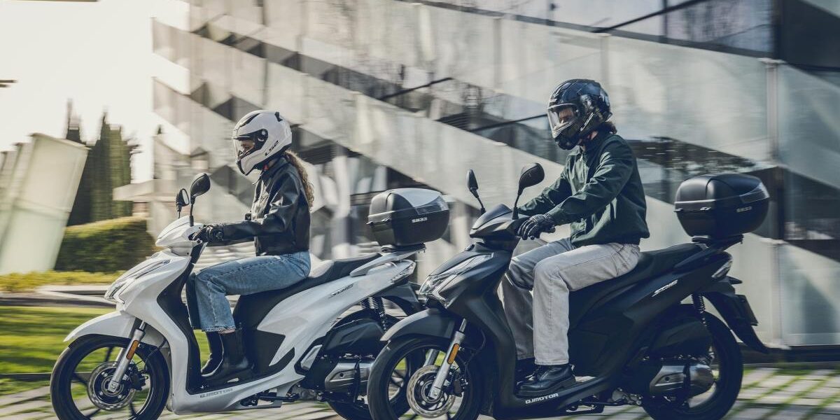 Comparativa entre un pequeño scooter de 125cc y una motocicleta tipo Naked apta para el carnet A2, aparcadas en las instalaciones de la autoescuela MotoCircuito en Móstoles.