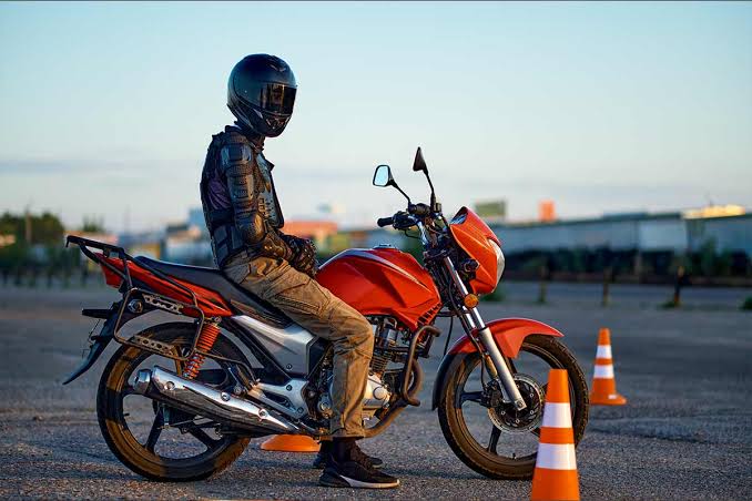 errores-examen-circulacion-moto-calle-dgt-madrid Motorista de la autoescuela MotoCircuito detenido correctamente ante una señal de STOP con un pie apoyado en el asfalto durante una práctica de circulación en Móstoles, seguido por el coche del examinador.