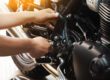 Detalle de un motorista aplicando grasa de mantenimiento en la cadena de su motocicleta nueva, aplicando los consejos aprendidos en la autoescuela MotoCircuito.