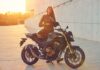 Una alumna sonriente de la autoescuela MotoCircuito equipada con casco y chaqueta, sentada con seguridad sobre una motocicleta de prácticas en el circuito de Móstoles.