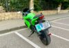 Detalle de la parte trasera de una motocicleta con la placa 'L' de conductor novel correctamente instalada mediante un soporte junto a la matrícula.