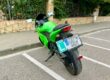 Detalle de la parte trasera de una motocicleta con la placa 'L' de conductor novel correctamente instalada mediante un soporte junto a la matrícula.