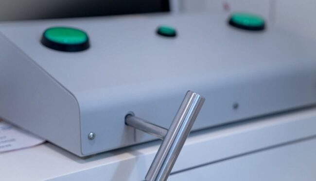 Detalle de las manos de un futuro motorista realizando la prueba de coordinación en la máquina de palancas durante el test psicotécnico para el carnet de moto.