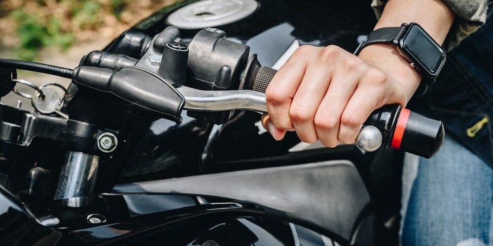 calar-moto-examen-practico-dgt-falta-eliminatoria-madrid Detalle de las manos de un alumno de MotoCircuito operando con precisión la maneta de embrague y el acelerador para evitar calar la motocicleta durante una práctica en Móstoles.