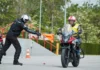 Alumno de la autoescuela MotoCircuito moviendo una motocicleta marcha atrás con el motor apagado, apoyando el vehículo de forma segura en la cadera durante el examen en Móstoles.