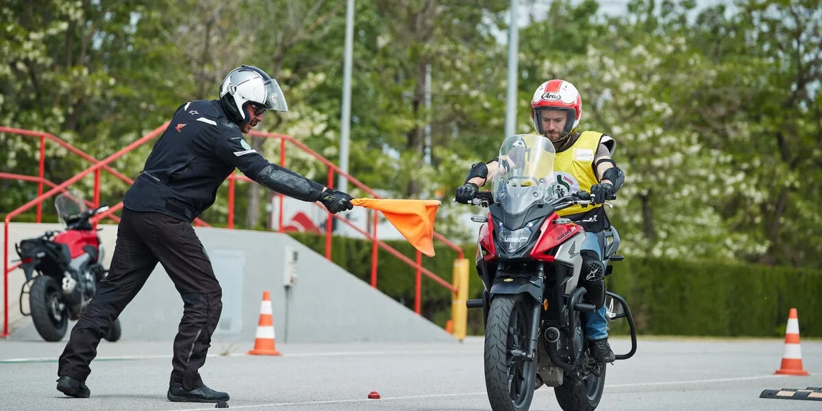 Alumno de la autoescuela MotoCircuito moviendo una motocicleta marcha atrás con el motor apagado, apoyando el vehículo de forma segura en la cadera durante el examen en Móstoles.