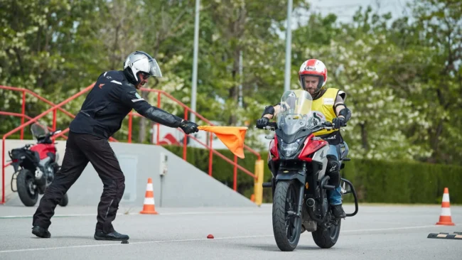 Alumno de la autoescuela MotoCircuito moviendo una motocicleta marcha atrás con el motor apagado, apoyando el vehículo de forma segura en la cadera durante el examen en Móstoles.